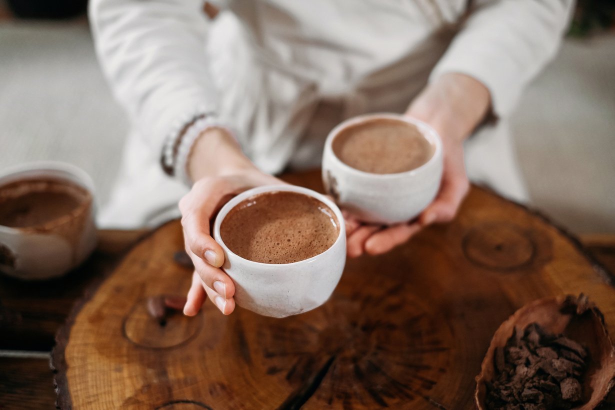 Person giving ceremonial cacao in cup. chocolate drink top view